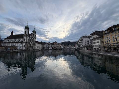 Scenic view of a river with historic buildings under dramatic skies.