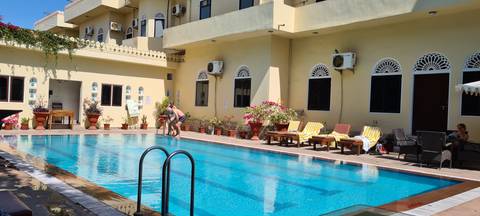 Outdoor swimming pool with sun loungers and people relaxing.