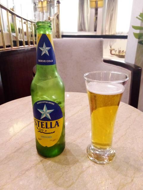 A bottle of Stella beer and a glass on a marble table.