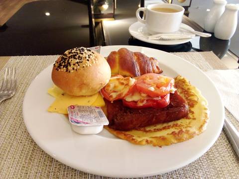 Breakfast plate with roll, croissant, and cheese.