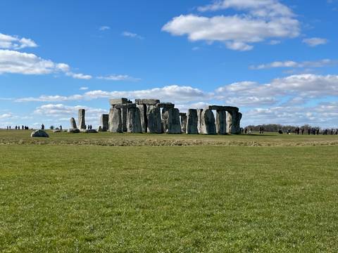       Stonehenge stone circle with tourists observing.
  