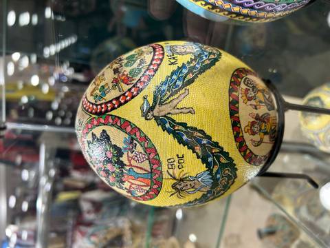 Decorated egg with cultural designs displayed indoors.