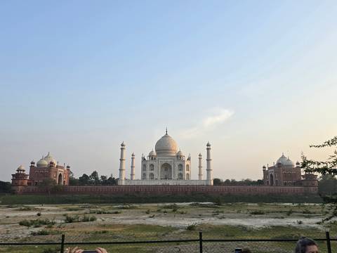       Wide view of the Taj Mahal from the riverside with clear sky.
  