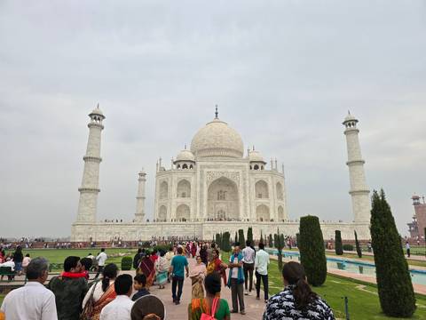       Front view of the Taj Mahal with crowds and gardens.
  