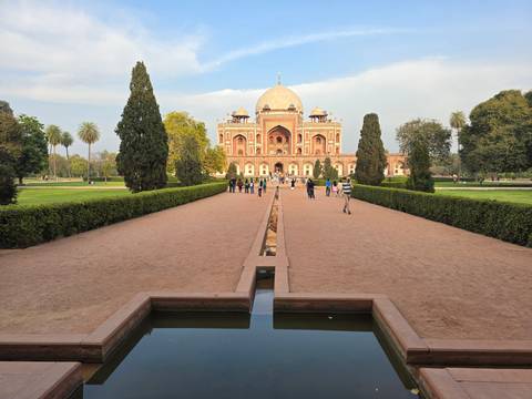       Mausoleum with red and white architecture surrounded by gardens.
  