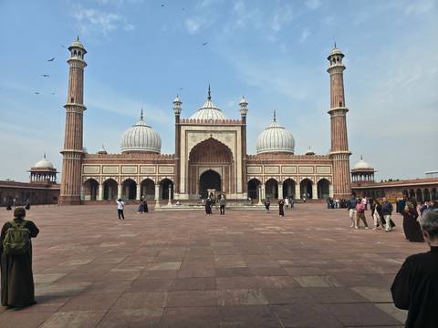       Visitors at a large mosque with three domes.
  