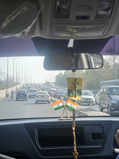 Traffic scene through a car windshield with Indian flags hanging.