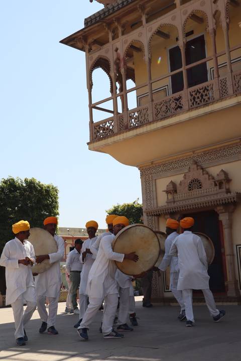 Group of men in traditional attire playing drums.