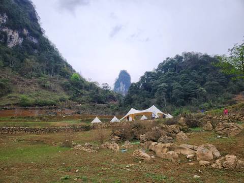       Tents set in a valley with limestone mountains.
  