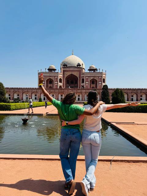 People posing with wide arms in front of Humayun's Tomb.