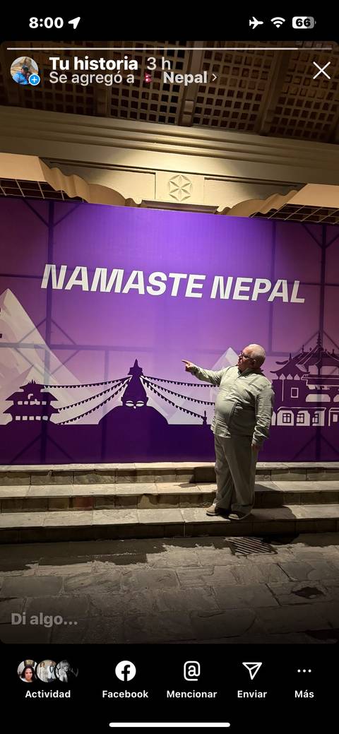 Person pointing at a decorative wall with Namaste Nepal text.