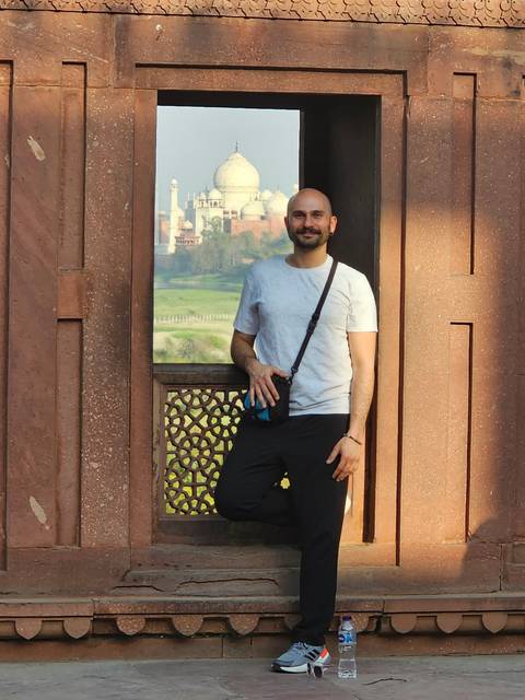       Person standing by a historic structure with a camera.
  