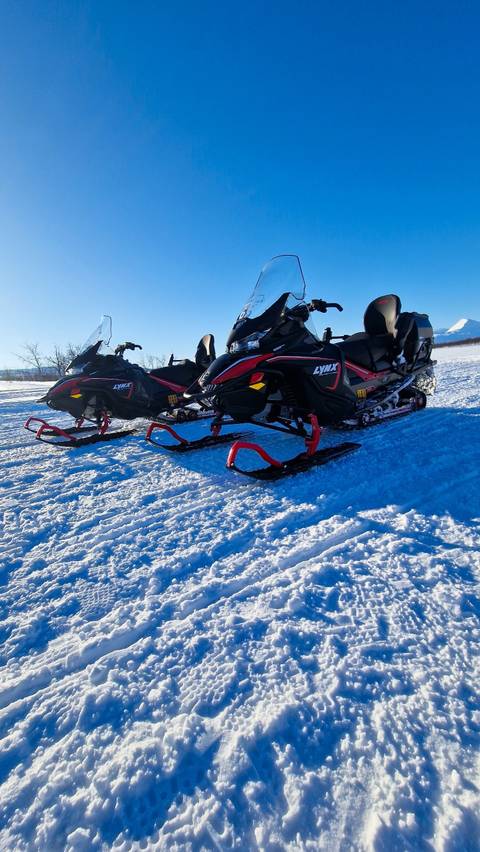 Two snowmobiles parked on a snowy field.