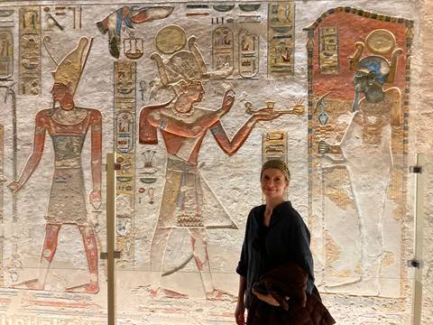 A person stands in front of a decorated ancient Egyptian wall.