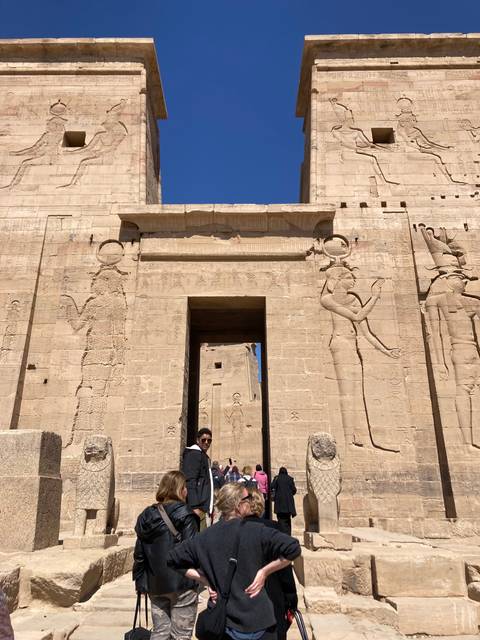 Person standing in front of an ancient Egyptian temple with hieroglyphics.
