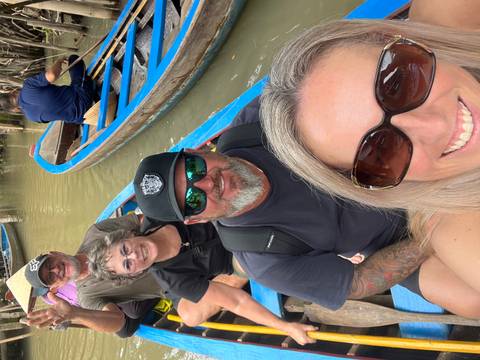       Group of people in a boat on a river surrounded by tropical greenery.
  