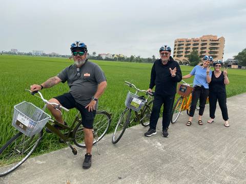 Group of people cycling through rice paddies.