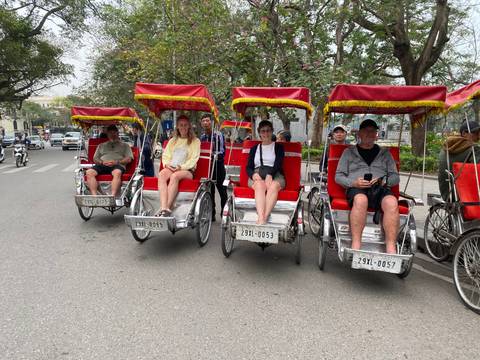       People sitting in red cycle rickshaws on a street.
  