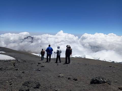 Four people at a mountain summit surrounded by clouds.