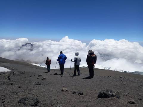 Hikers standing on a mountain top with cloudy background.