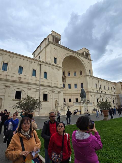       Large architectural structure with classical design in courtyard with visitors.
  