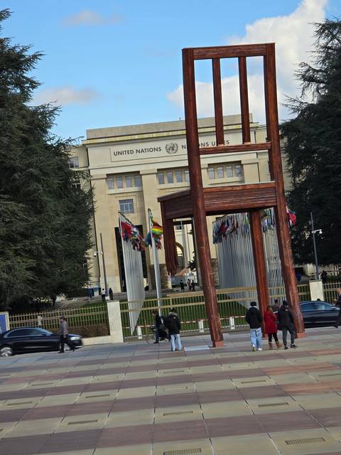       Building of United Nations with flags and large sculpture.
  
