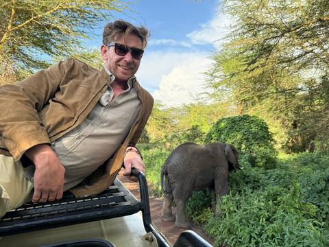 Man on safari with elephant in the background.