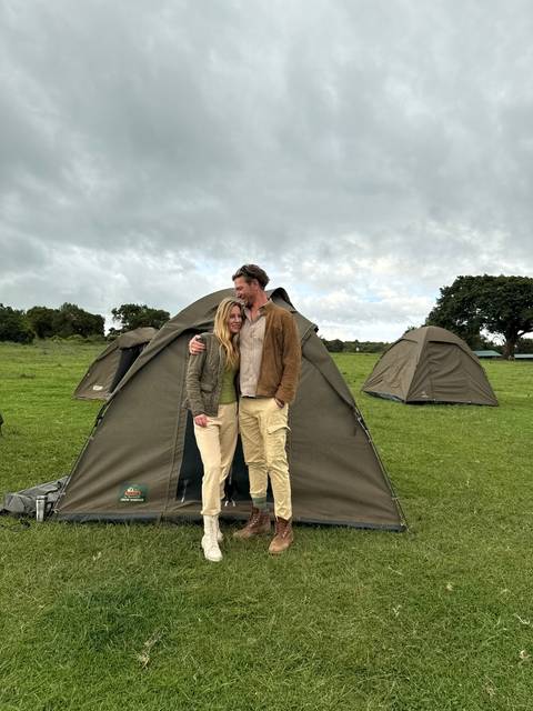 Couple standing in front of a tent in a safari camp.