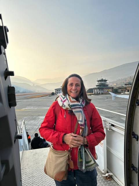 Person smiling at the airport with mountains in the background.