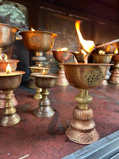 Close-up of lit oil lamps in a shrine.