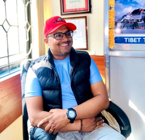 Person smiling indoors wearing a red cap.