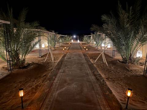       Luxurious desert camp setup with carpets and traditional lamps at night.
  