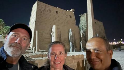       People posing in front of Luxor Temple at night.
  