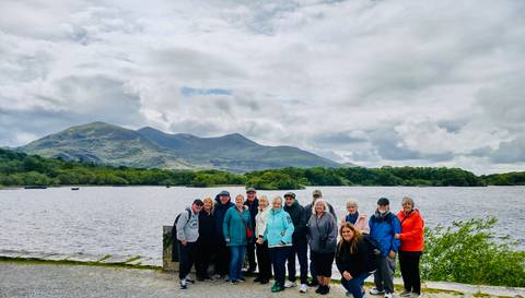       Group photo by a lake with mountains.
  