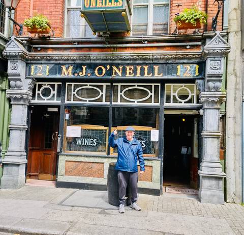       Man standing in front of a traditional Irish pub.
  