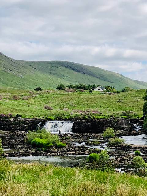       Waterfall on a green hill with house.
  