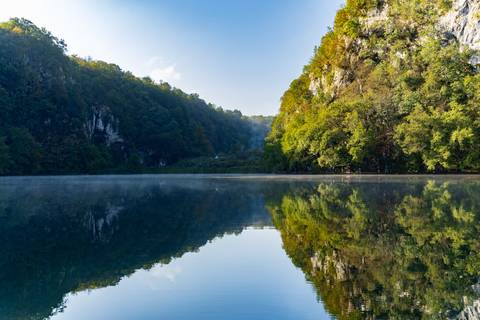 Still lake reflecting surrounding lush green hills.