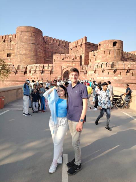 Couple in front of a large historic fort with crowds.