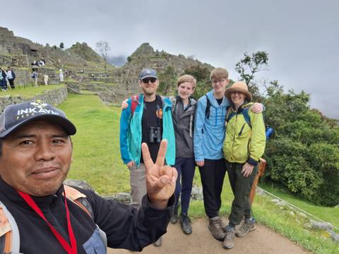 Group posing in front of visible Machu Picchu ruins.