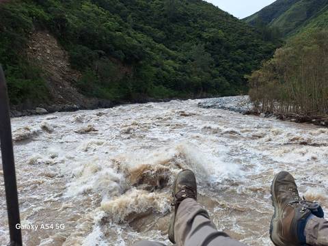 Rushing river view with shoes visible over the water.