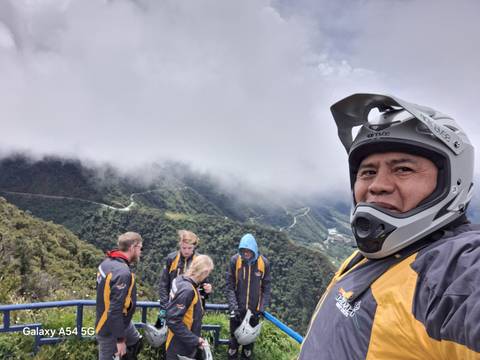 Group of people in helmets at a mountainous lookout.