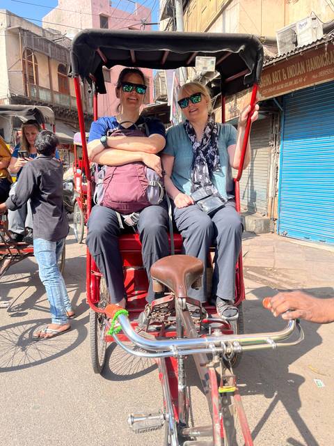 Two people sitting on a rickshaw with an urban background.