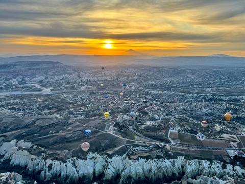 Aerial view of hot air balloons over Cappadocia at dawn.