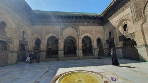 A courtyard with intricate arches and a person in traditional dress.