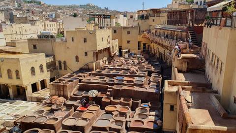       Wide view of an ancient tannery with people working.
  
