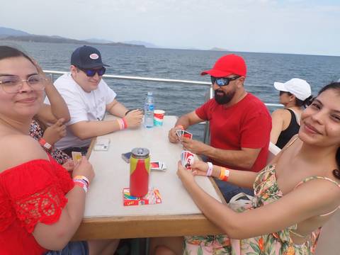 Group of people playing cards on a boat.