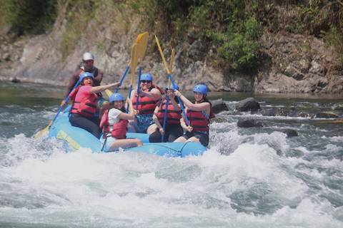       Group of people rafting on a river with paddles.
  
