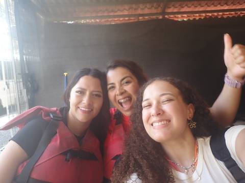       Three women wearing life vests, smiling and posing.
  