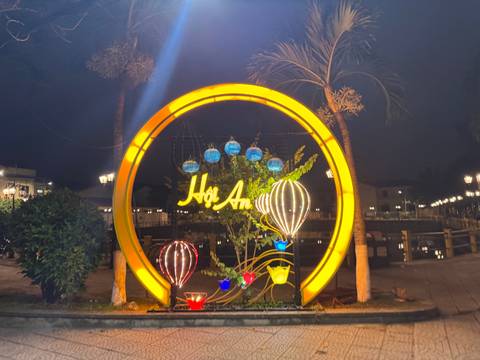       Illuminated sign of Hoi An with decorative elements at night.
  