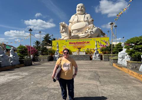       Person posing in front of a large statue with decorative elements.
  